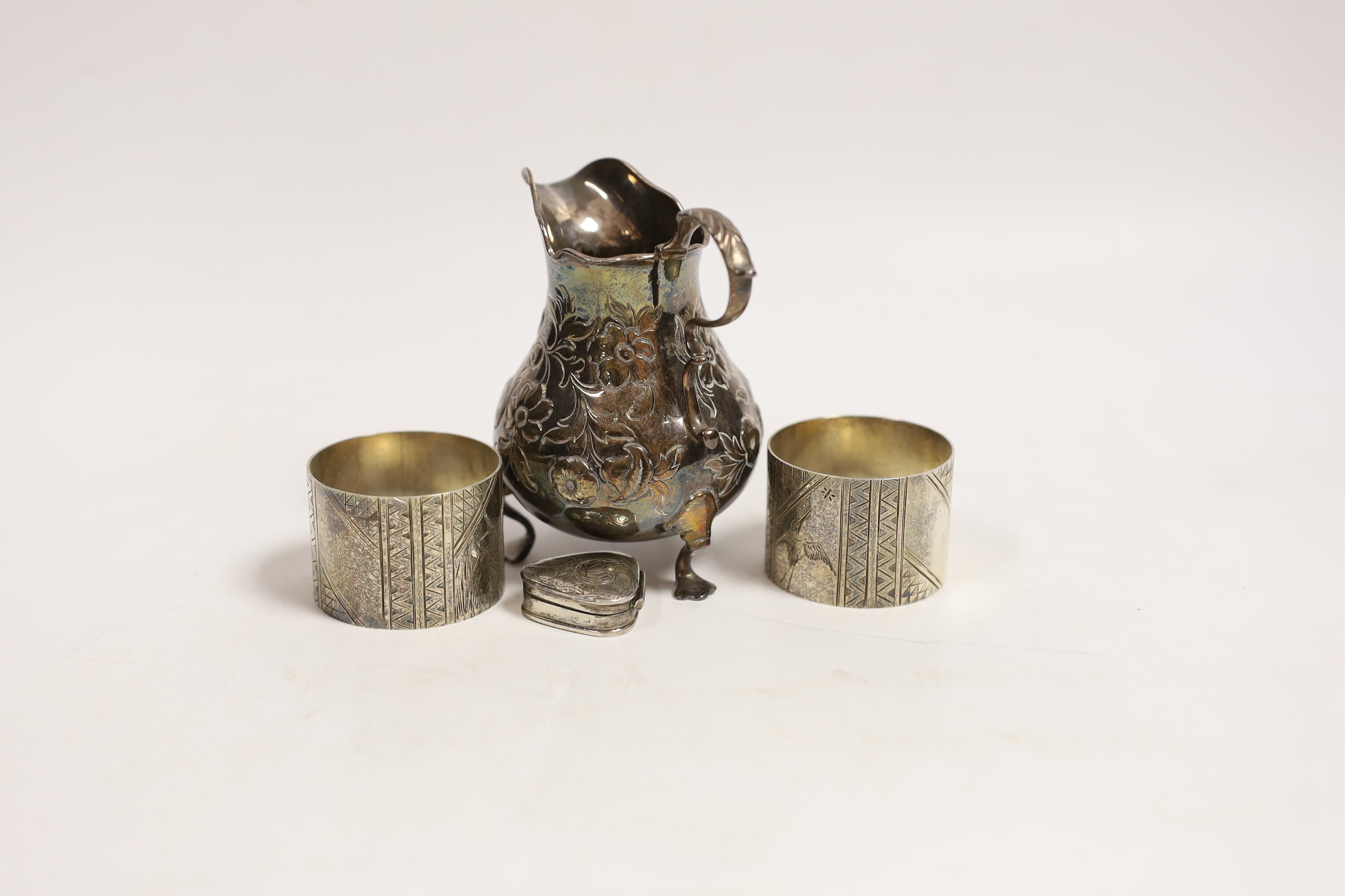 A Victorian silver baluster cream jug, London, 1846, 95mm, a pair of Victorian silver napkin rings engraved with aesthetic decoration, Charles Edwards, London, 1880 and a modern silver pill box.